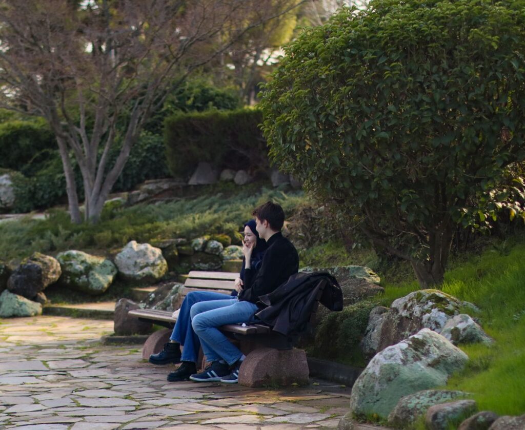 A couple sitting on a park bench having a calm conversation surrounded by greenery