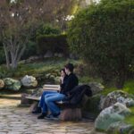 A couple sitting on a park bench having a calm conversation surrounded by greenery