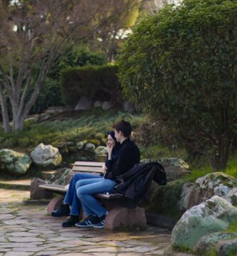 A couple sitting on a park bench having a calm conversation surrounded by greenery