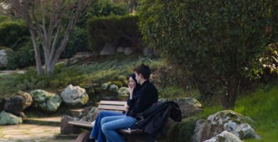 A couple sitting on a park bench having a calm conversation surrounded by greenery