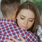 A young couple embracing indoors, expressing comfort and emotional support