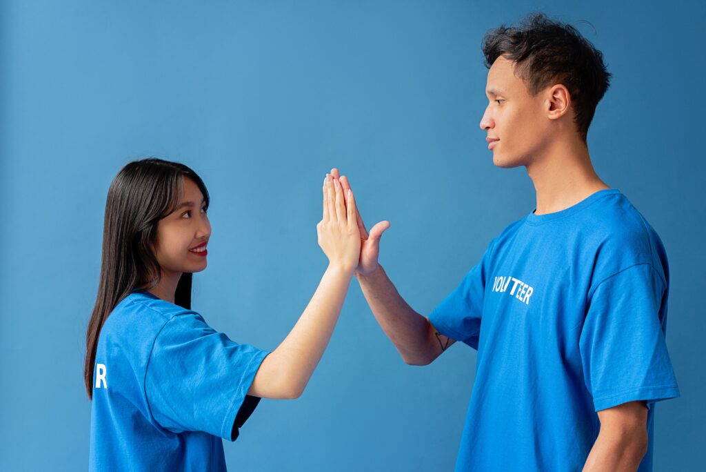 Two people in blue shirts high-fiving against a blue background, symbolizing teamwork and partnership in a relationship