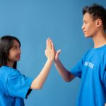 Two people in blue shirts high-fiving against a blue background, symbolizing teamwork and partnership in a relationship