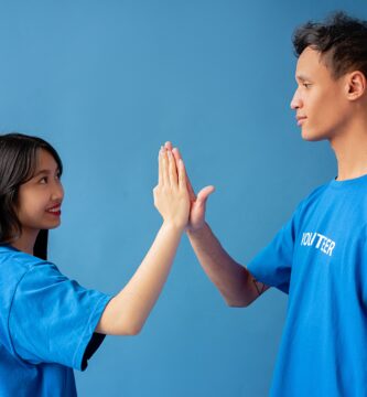 Two people in blue shirts high-fiving against a blue background, symbolizing teamwork and partnership in a relationship