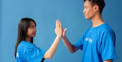 Two people in blue shirts high-fiving against a blue background, symbolizing teamwork and partnership in a relationship