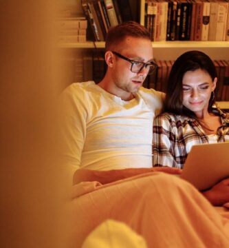 A couple enjoying a cozy evening reading together on a tablet in a home library, symbolizing quiet connection and understanding different social needs in relationships.