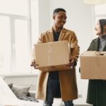 A couple happily unpacking boxes together in their new home, sharing a warm moment while moving in