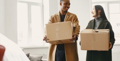 A couple happily unpacking boxes together in their new home, sharing a warm moment while moving in