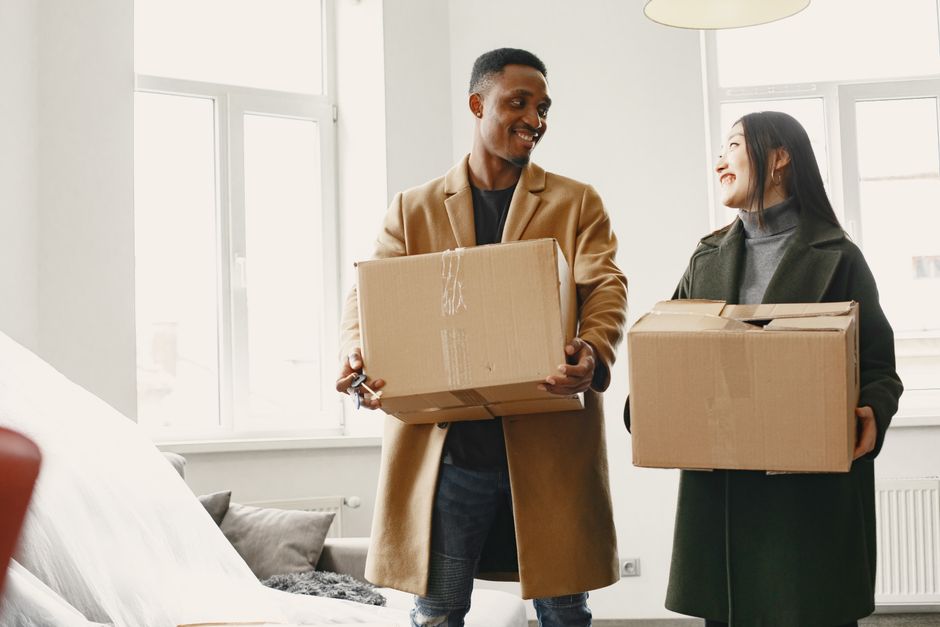A couple happily unpacking boxes together in their new home, sharing a warm moment while moving in